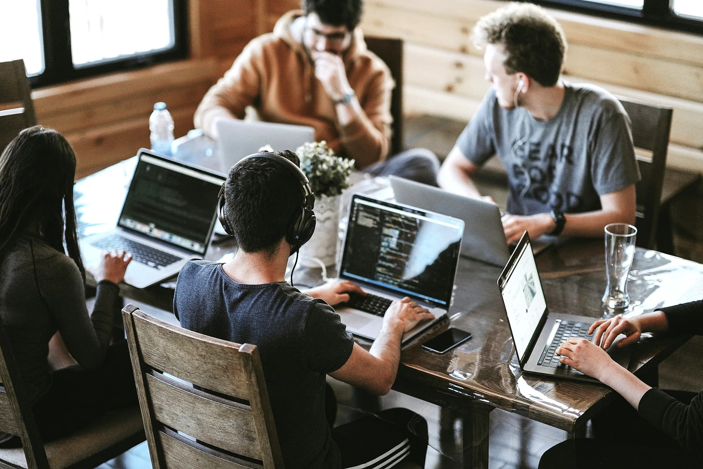 A team around a long table in a bright meeting room, each of them on a laptop